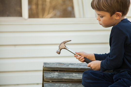 Young boy repairing cubbyhouse with nails