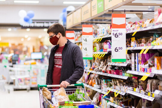 Young male person grocery shopping for essentials with face mask protection from spreading covid-19