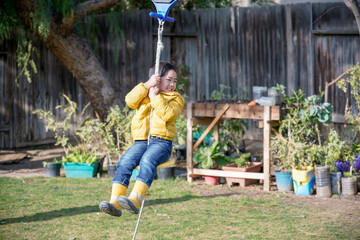 The boy playing zip lining in the backyard