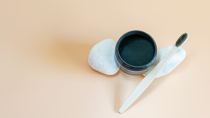 Teeth whitening activated organic charcoal powder and bamboo toothbrush on natural white stones, health and teeth care concept.