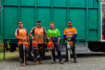 Portrait of a team of men who are tree felling lumberjacks with their chainsaws in front of truck