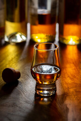 Dram of single malt scotch whisky and bottles on background