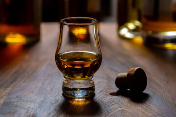 Dram of single malt scotch whisky and bottles on background