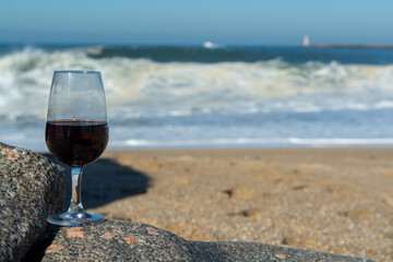 Tasting of different fortified dessert ruby, tawny port wines in glasses on sandy beach with view on waves of Atlantic ocean near Vila Nova de Gaia and city of Porto, Portugal