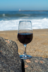 Tasting of different fortified dessert ruby, tawny port wines in glasses on sandy beach with view on waves of Atlantic ocean near Vila Nova de Gaia and city of Porto, Portugal