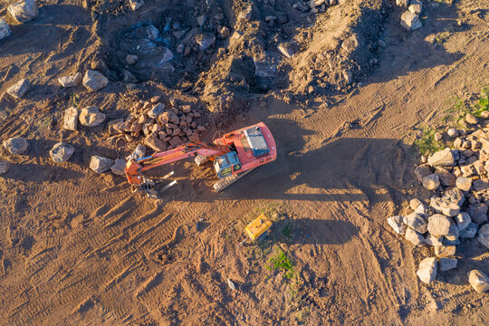 Aerial view of earth moving machinery shifting boulders in a paddock