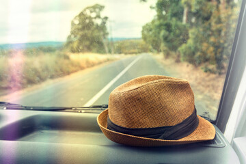 hat on the dashboard of a car on a road trip, with light leak
