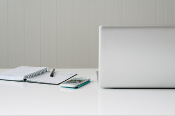 laptop, phone and diary on a white desk
