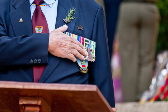 Veteran with his hand on his heart and medals during an Anzac service