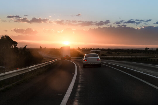 Sunrise on the highway, following a truck and sedan