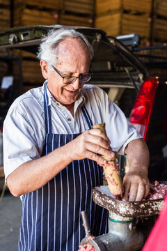 mobile butcher pushing meat through mincing machine