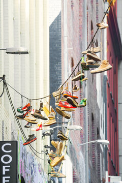 A collection of footwear hanging in a city laneway