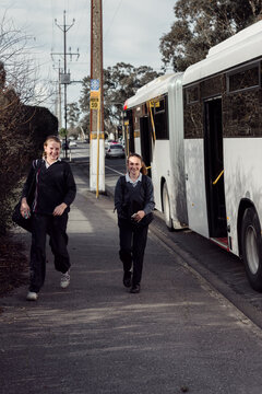 two teen high school students getting off the bus after school