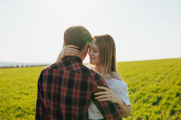 Young couple having good time on a beautiful green spring field. Joyful couple is hugging on green field.