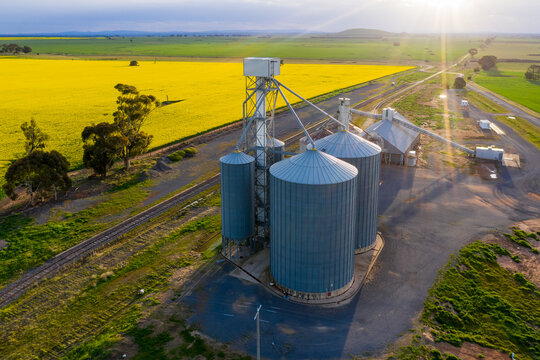 Aerial view of a grain silo along side a railway line and a canola field