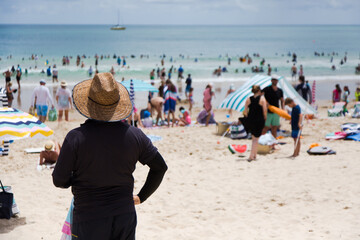 Man wearing a straw hat and rashie at noosa main beach