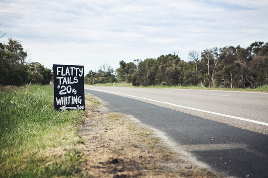 Black and white roadside sign advertising flathead tails horizontal