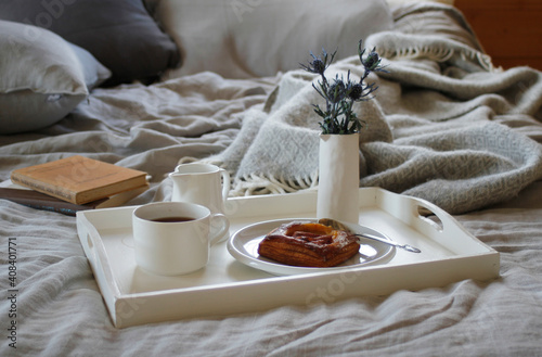 Breakfast tray on bed with grey linen and books