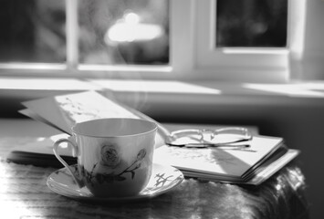 High key light Hot tea with steaming in black and white, Still life cuppa tea with steam on a coffee table with morning light shining from window, Cozy scene of relaxing in afternoon in tearoom
