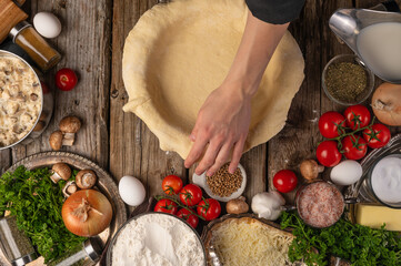 The chef prepares and works with the dough to make a pie. Cooking ingredients tomatoes, onions, mushrooms and meat. Top view. Cooking cooking concept and recipe book.