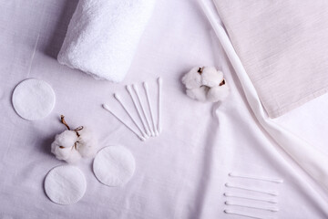 Obraz na płótnie Canvas white cotton flowers and clean towels, cotton pads, sticks, flat lay. Natural cotton fabric texture