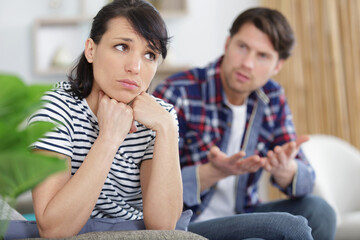 emotional upset couple sitting on couch and quarreling about smartphone