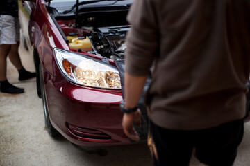 Two mechanics inspect the headlight of a vehicle.
