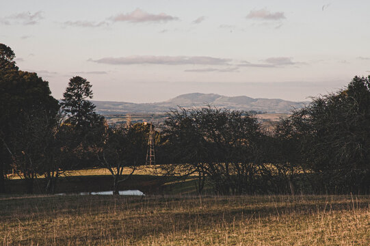country pasture view at sunset with a windmill and mountains in th background