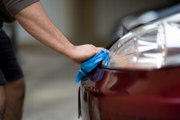A mechanic cleans headlights on a car during a routine service.