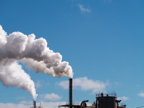 Plumes of steam rising from industrial chimneys into a blue sky