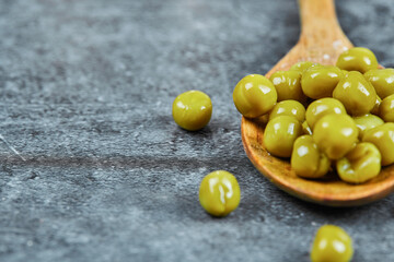 A wooden spoon of boiled green peas on a marble background