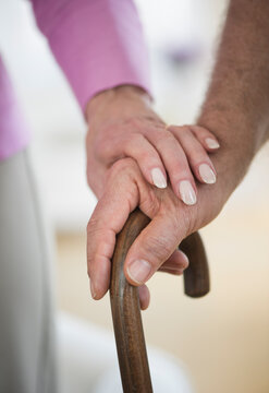 Close-up of senior couple hands on cane