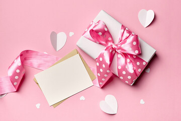 Greeting card mockup with gift box and paper hearts on pink background