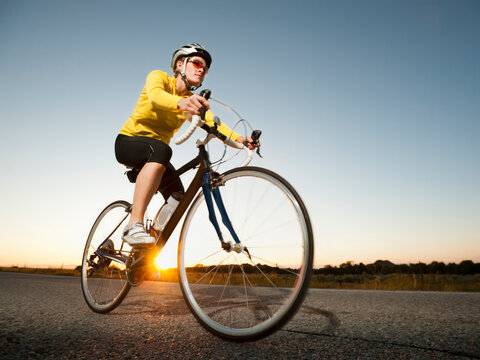 Mid adult woman cycling on empty road