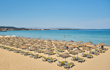 Empty sunbeds and parasols on morning, by the sea. Sand beach in luxury hotel resort near sea. Beautiful morning seascape.