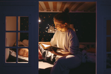 Mother reading book to sleeping daughter