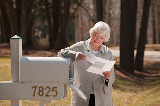 USA, Virginia, Richmond, senior woman reading letters by mailbox