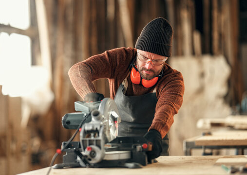 Joiner working with electric machine in workshop