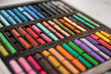 Multicolored artists soft pastels, chalks, crayons in the box. Spectrum of colors. Background. Selective focus.