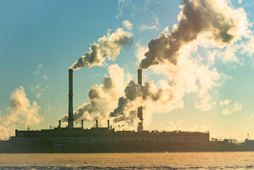Factory pipe polluting air, smoke from chimneys against sun, environmental problems, ecological theme, industry scene