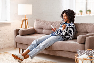 Ethnic female using smartphone on sofa
