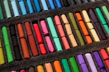 Naklejka premium Multicolored artists soft pastels, chalks, crayons in the box. Spectrum of colors. Background. Selective focus.