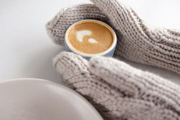 Women's mittened hands hold a coffee mug