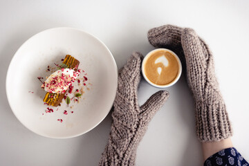 Women's mittened hands hold a coffee mug