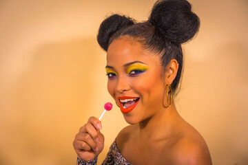 A sexy sensual woman with bright makeup and two side bun hairstyle holding a lollipop