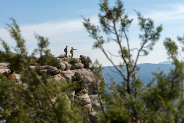 Two climbers standing on top of summit pointing with hand