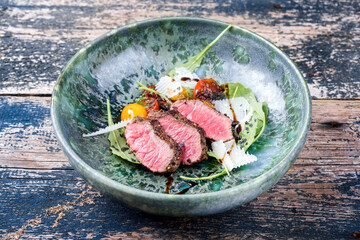 Modern Style Italian tagliata di manzo with dry aged sliced sirloin steak and lamb salad served as close-up in a design ceramic bowl © HLPhoto