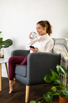 Woman Checks Her Phone While Sipping Her Drink