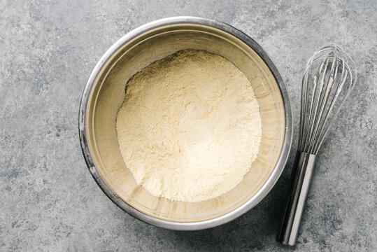 Cornmeal mix in a stainless steel bowl with a wire whisk