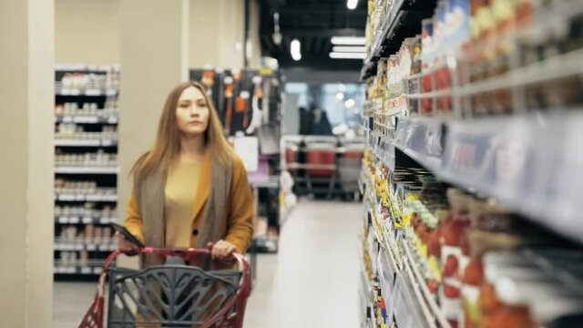 A young woman scans the barcode on the product and puts it in the basket to find out the price tag. New smart technologies.